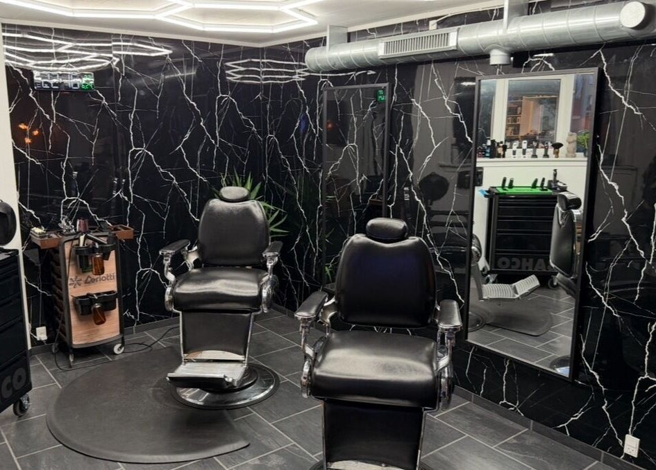 Elegant barber chairs at B the barber, Tórshavn, Streymoyar, FO, with sleek black decor and mirrors.