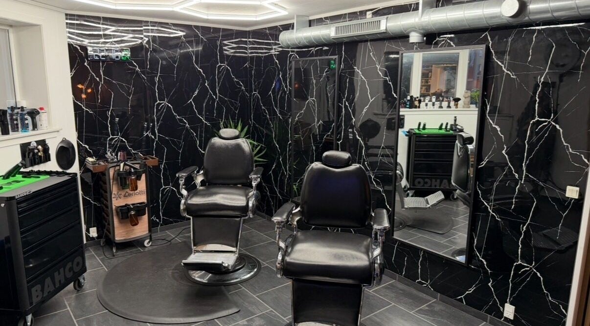 Elegant barber chairs at B the barber, Tórshavn, Streymoyar, FO, with sleek black decor and mirrors.
