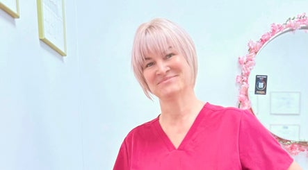 Smiling professional at Lotus Skin, Beauty and Wellness, Mansfield, England, GB with a floral mirror backdrop.