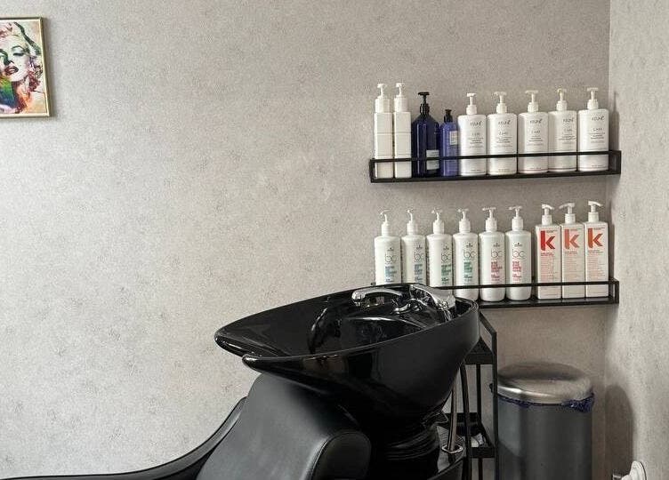 Stylish shampoo station at MSBeauty, Rīga, LV with shelves of hair products on a sleek gray wall.