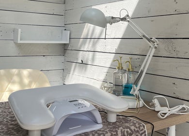 Cozy nail station at Glow Nails, Bournemouth, England, GB with lamp and sanitizer on a wooden desk.