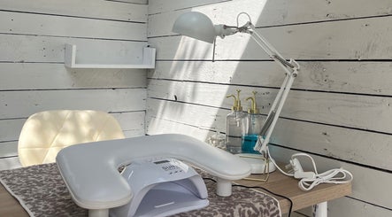 Cozy nail station at Glow Nails, Bournemouth, England, GB with lamp and sanitizer on a wooden desk.