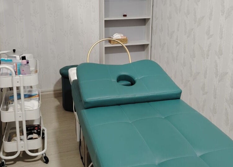 Relaxing treatment room at TMH SALON & SPA, Doha, Doha Municipality, QA featuring a teal massage bed.