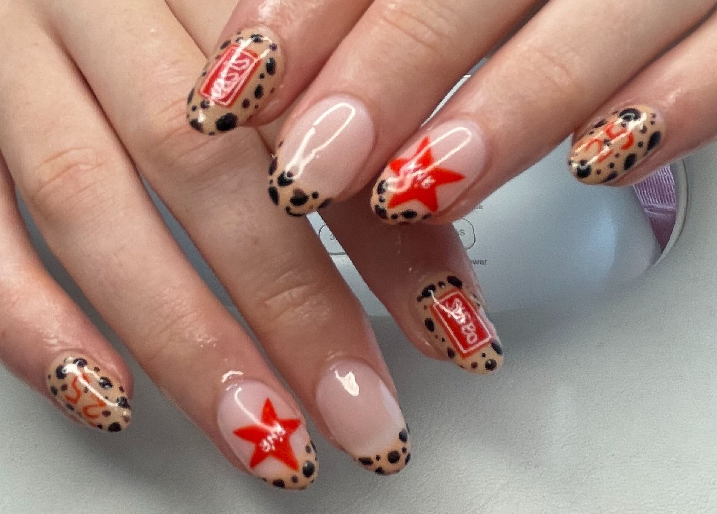 Stylish hand nail design at Nails by Chloe, Marske-by-the-sea, England, GB featuring red stars and leopard print.