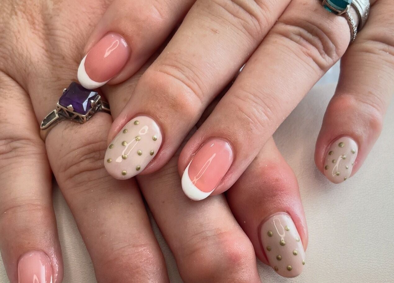 Close-up of chic nail design at Nails by Chloe, Marske-by-the-sea, England, GB with French tips and gold dots.