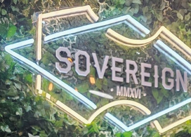 Illuminated Sovereign sign amidst green foliage in Aberdeen, Scotland, GB.