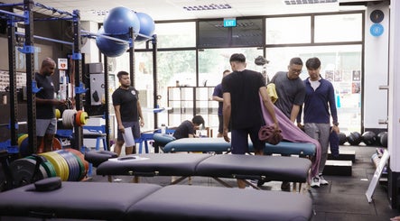 Active wellness space at Knead Therapy Kovan, Singapore, SG, showcasing massage tables and gym equipment.