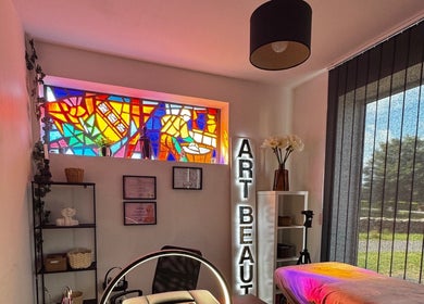 Salle esthétique au vitrail coloré à Maison Mélyne, Bertrichamps, Grand Est, FR. Atmosphère chaleureuse et moderne.