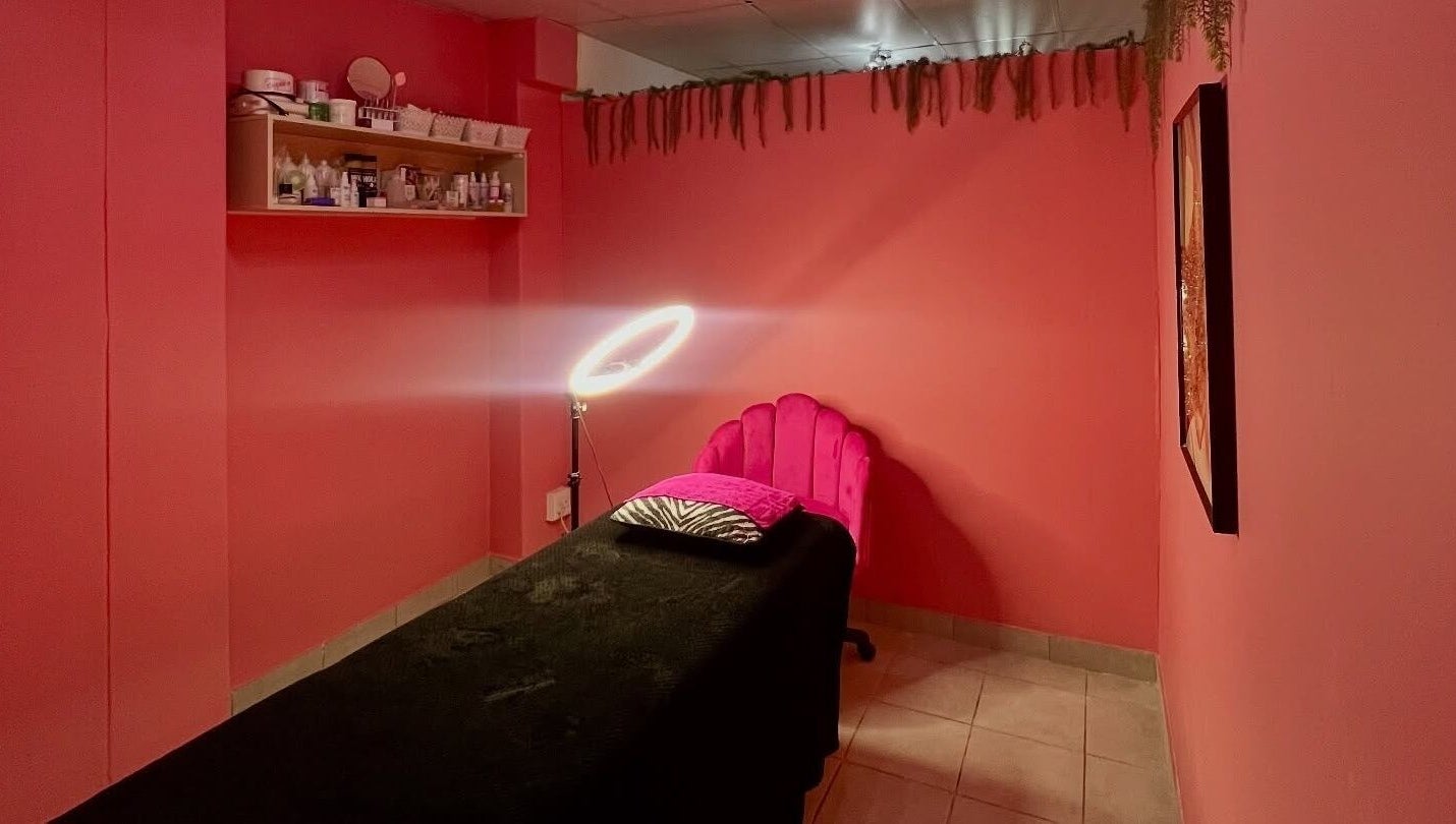A cozy treatment room at Peaches Beauty Bar, Edenvale, Gauteng, ZA, with pink walls and ambient lighting.