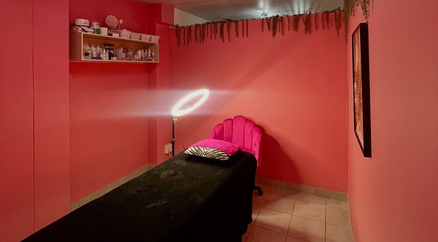 A cozy treatment room at Peaches Beauty Bar, Edenvale, Gauteng, ZA, with pink walls and ambient lighting.