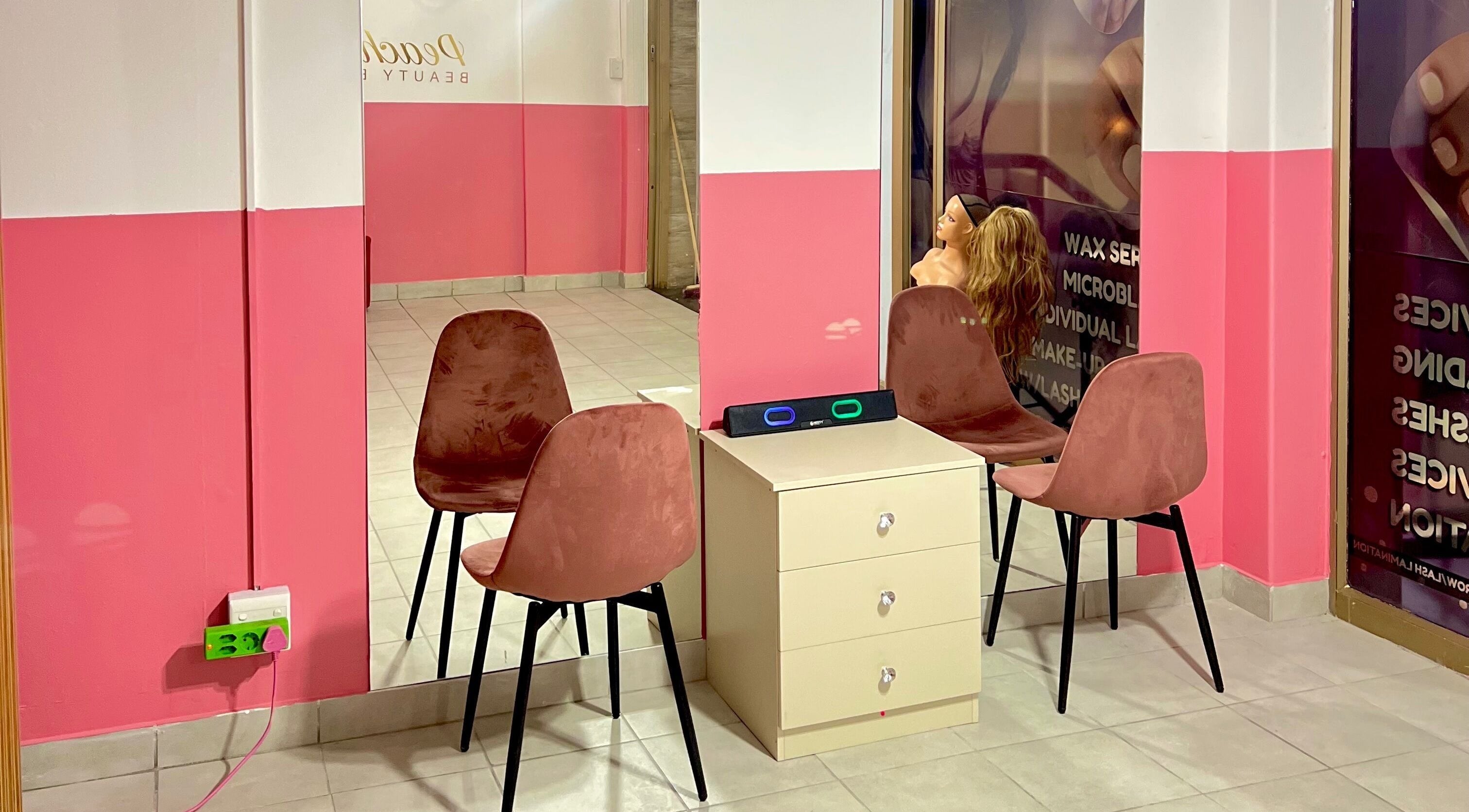 Cozy seating area at Peaches Beauty Bar, Edenvale, Gauteng, ZA with pink decor and modern chairs.
