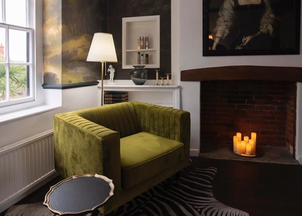 Cozy corner at Jack & the Wolfe with velvet chair, fireplace in Lymington, England, GB.