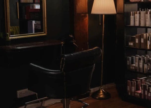 Cozy salon chair at Jack & the Wolfe, Lymington, England, GB, beside shelves of premium products.