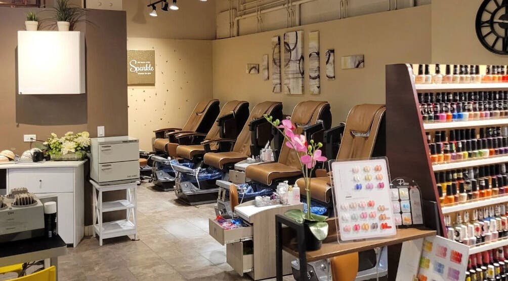 Interior of Sparkle Nail Salon in Chicago, Illinois, US, featuring plush pedicure chairs and colorful nail polish display.