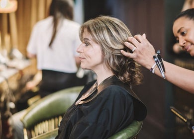 Stylist perfecting hairstyle at Alchemy & I, Berkhamsted, England, GB. Relaxed salon atmosphere.