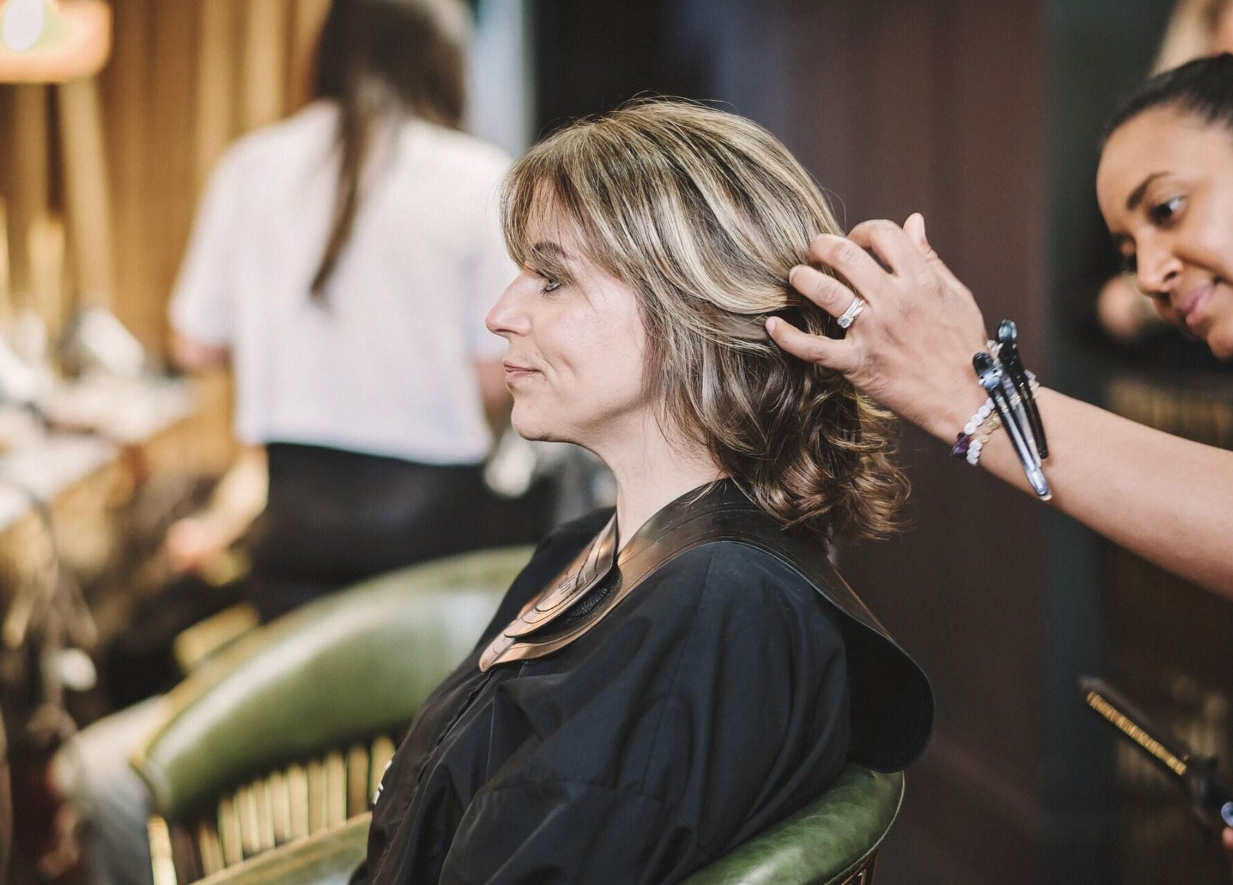 Stylist perfecting hairstyle at Alchemy & I, Berkhamsted, England, GB. Relaxed salon atmosphere.