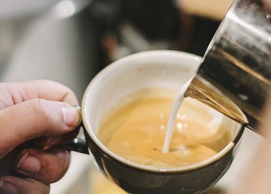Barista pouring milk into coffee at Alchemy & I, Berkhamsted, England, GB.