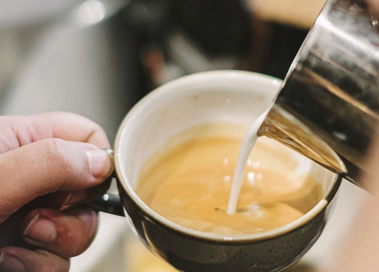 Barista pouring milk into coffee at Alchemy & I, Berkhamsted, England, GB.