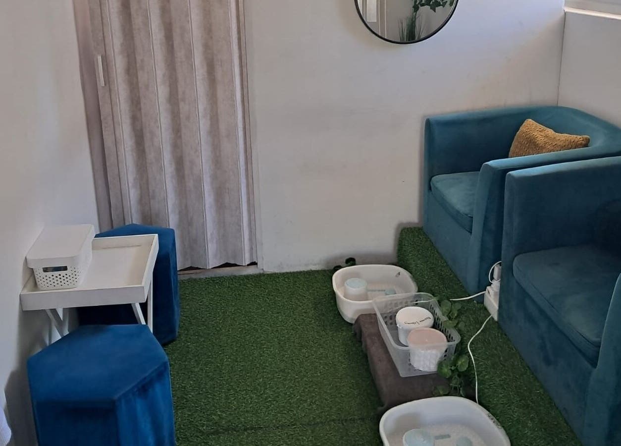 Relaxing seating area at Ispa Aesthetics, Cape Town, Western Cape, ZA, featuring plush blue chairs and spa amenities.