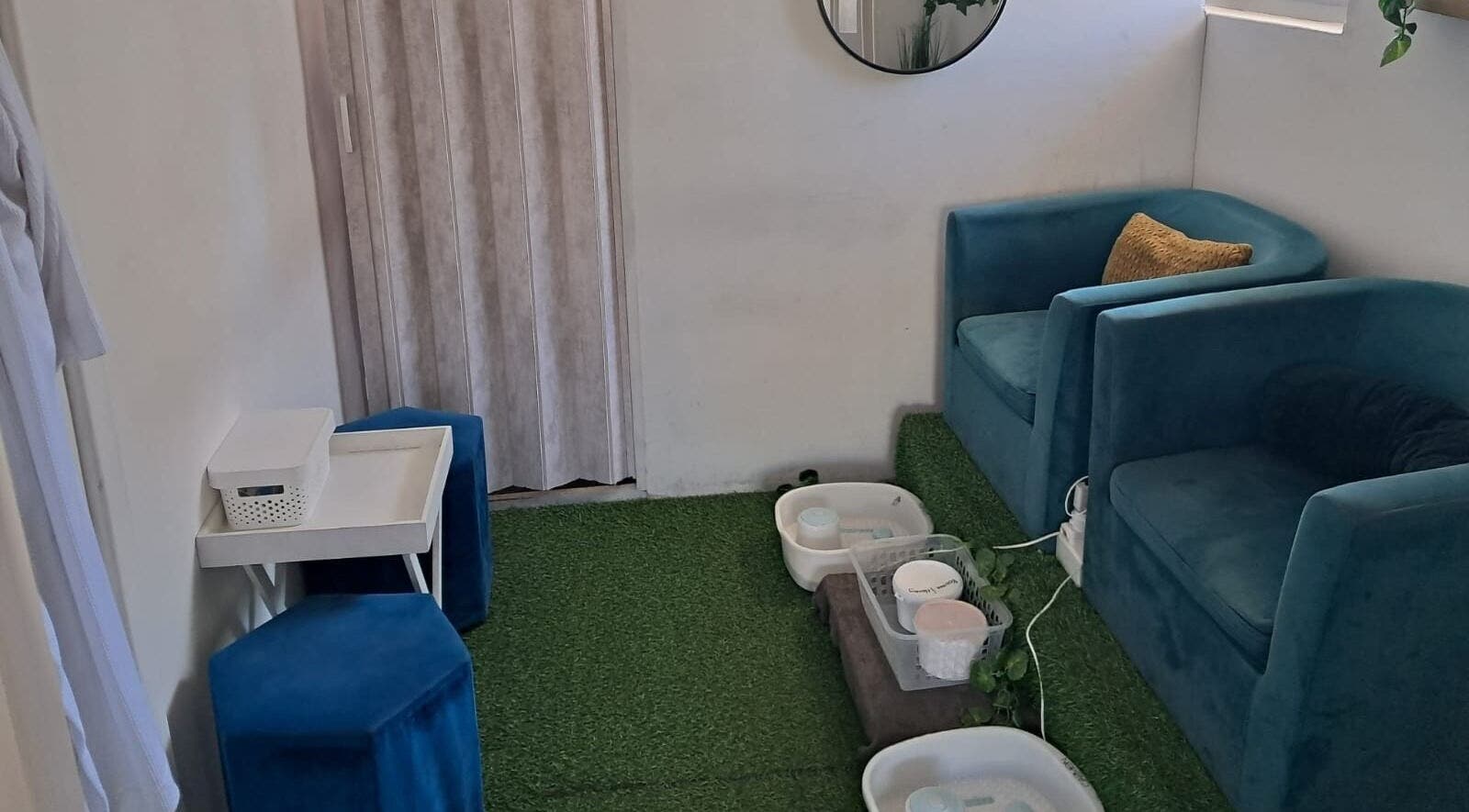 Relaxing seating area at Ispa Aesthetics, Cape Town, Western Cape, ZA, featuring plush blue chairs and spa amenities.