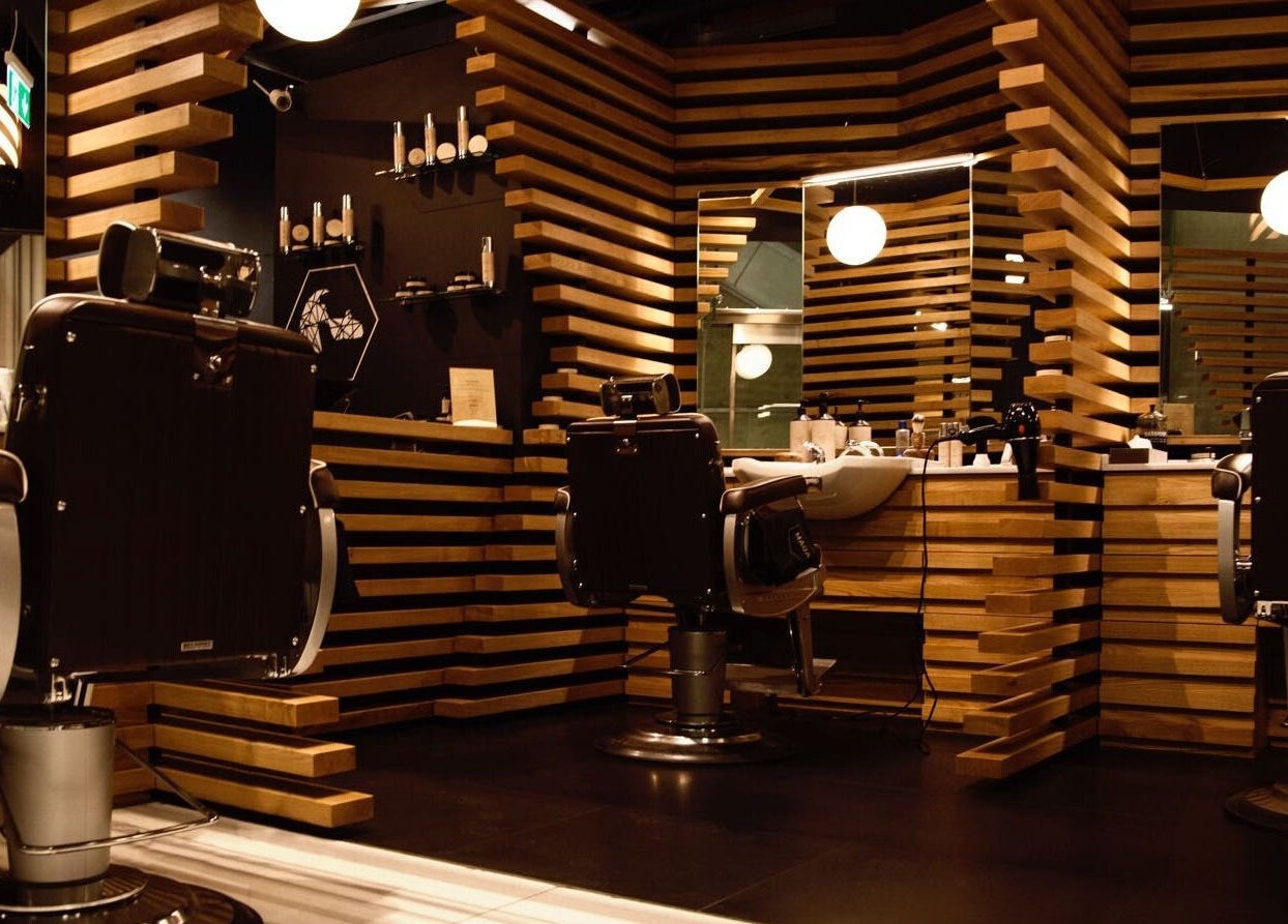 Elegant barber chairs and mirrors at ADAM Grooming Atelier - Canary Wharf Jubilee Station, London, England, GB.