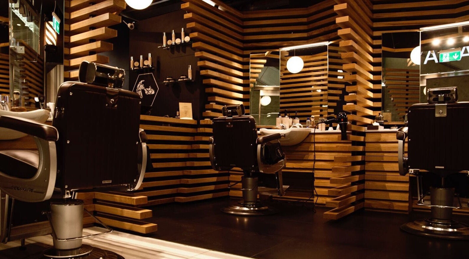 Elegant barber chairs and mirrors at ADAM Grooming Atelier - Canary Wharf Jubilee Station, London, England, GB.