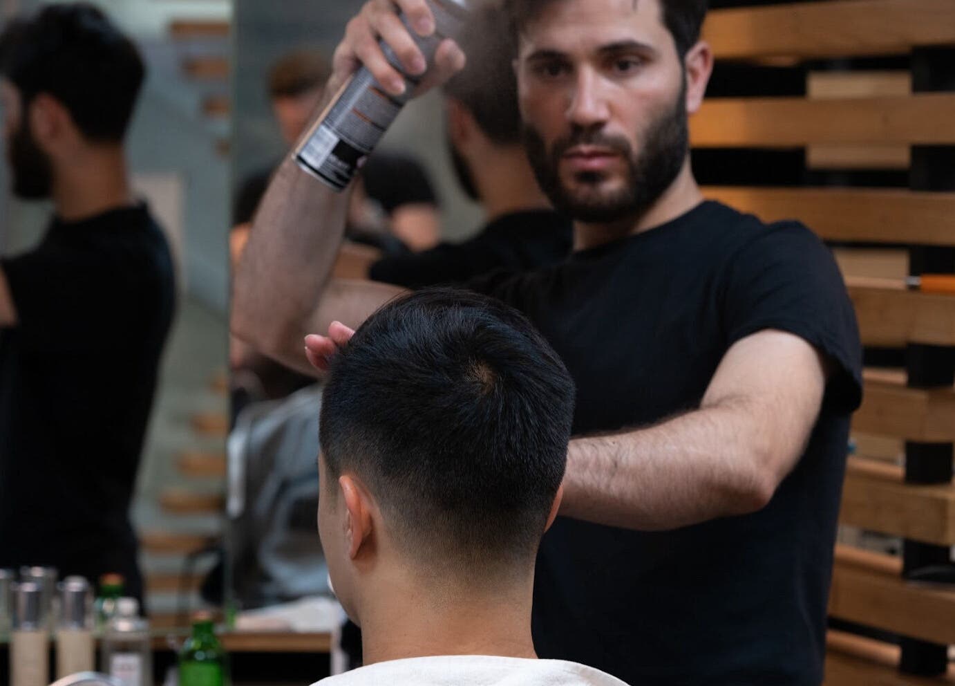 Barber styling hair at ADAM Grooming Atelier - Canary Wharf Jubilee Station, London, England, GB.