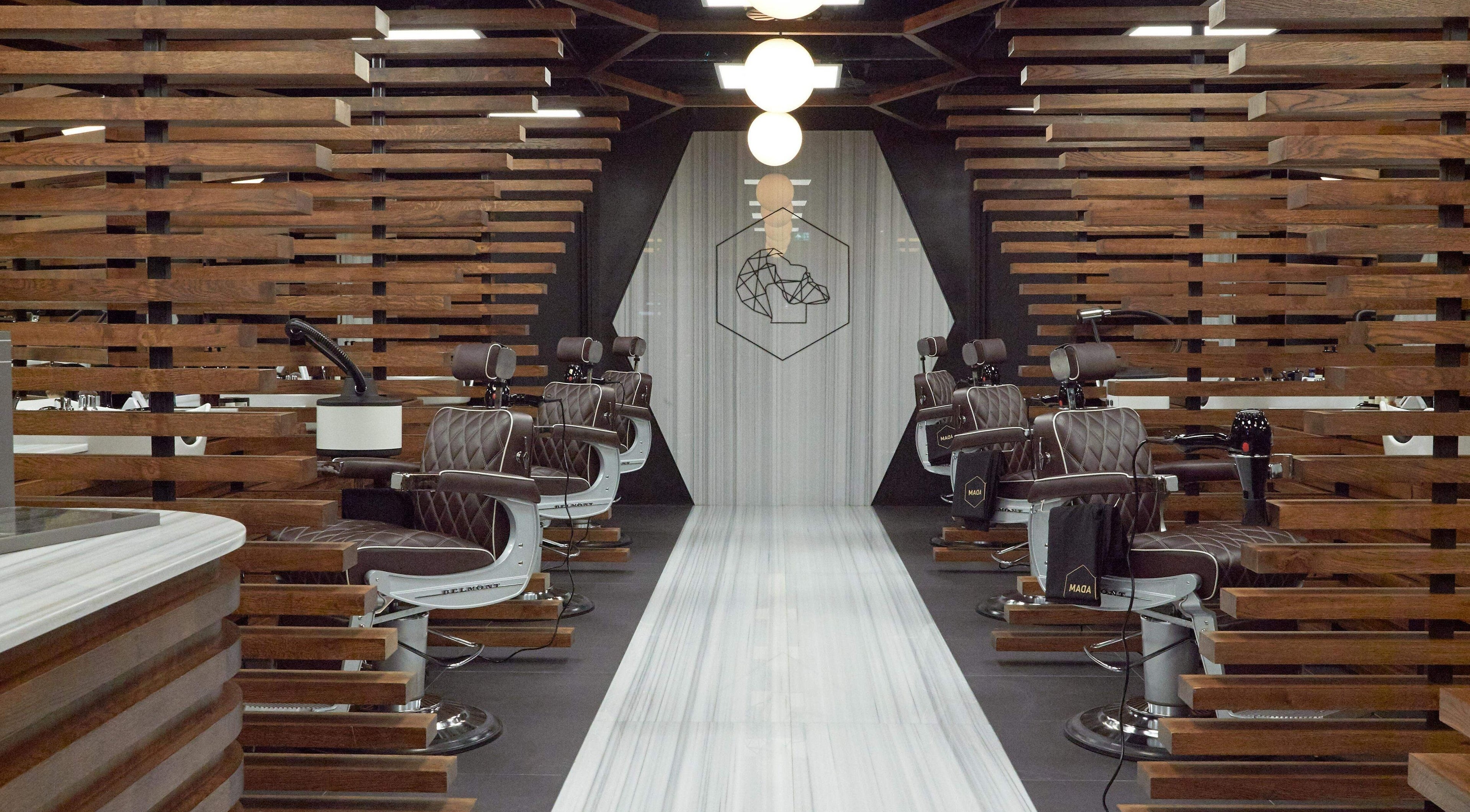 Modern interior of ADAM Grooming Atelier - Harrods in London, England, GB, featuring sleek barber chairs.