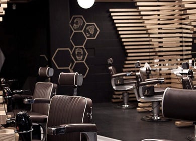Modern interior of ADAM Grooming Atelier - Fitzrovia, London, England, GB, featuring sleek barber chairs.