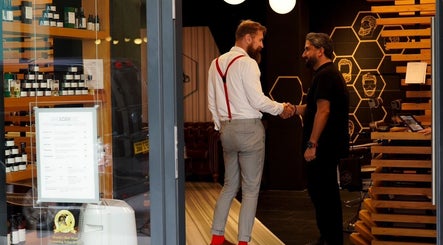 Reception area of ADAM Grooming Atelier - Fitzrovia in London, England, GB, showcasing a welcoming handshake.