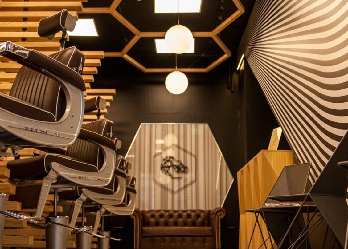 Modern barber chairs at ADAM Grooming Atelier - Monument in London, England, GB with stylish wall art.