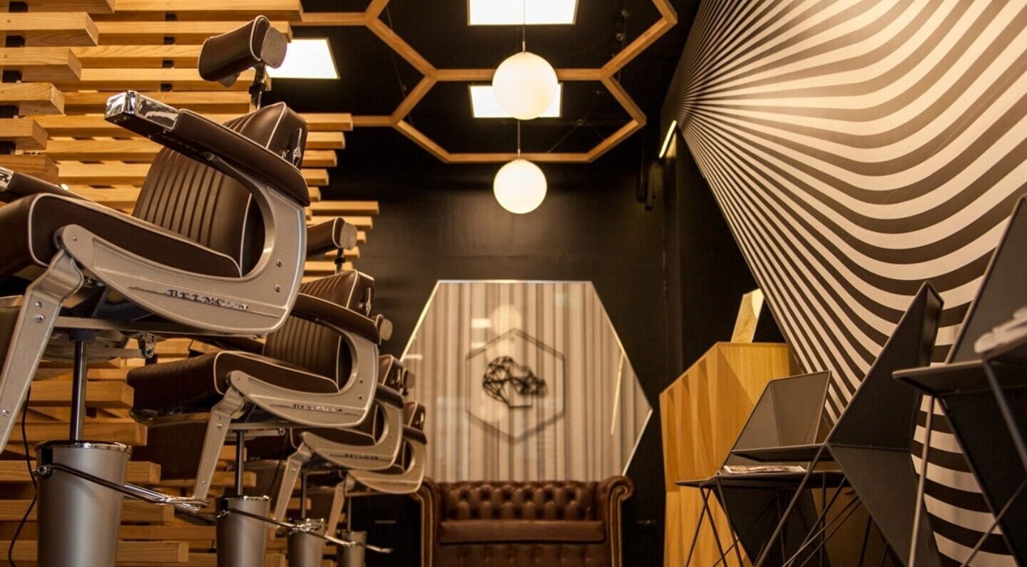 Modern barber chairs at ADAM Grooming Atelier - Monument in London, England, GB with stylish wall art.