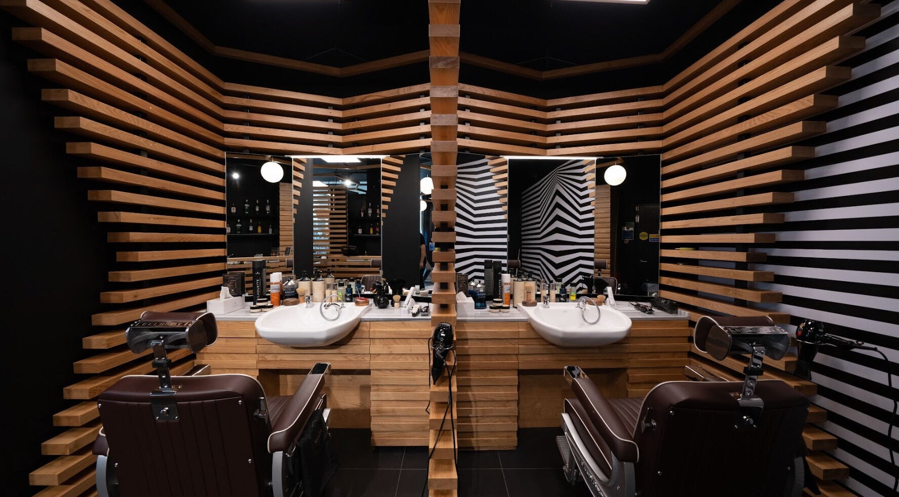 Chic interior of ADAM Grooming Atelier - Canary Wharf Cabot Place, London, England, GB. Stylish barber chairs and decor.