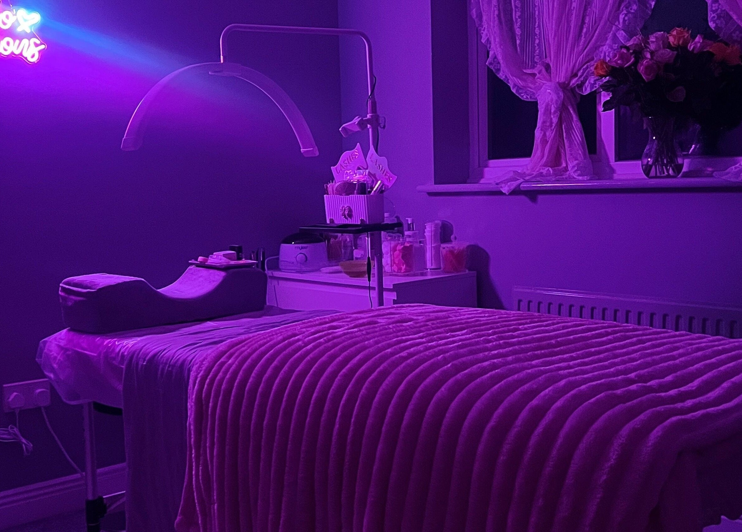 Relaxing beauty room at Faces Enhanced, Nottingham, England, GB with purple lighting and plush decor.