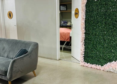 Stylish lounge area at Beauty By Kelly in Boksburg, Gauteng, ZA, featuring a plush grey sofa and floral decor.