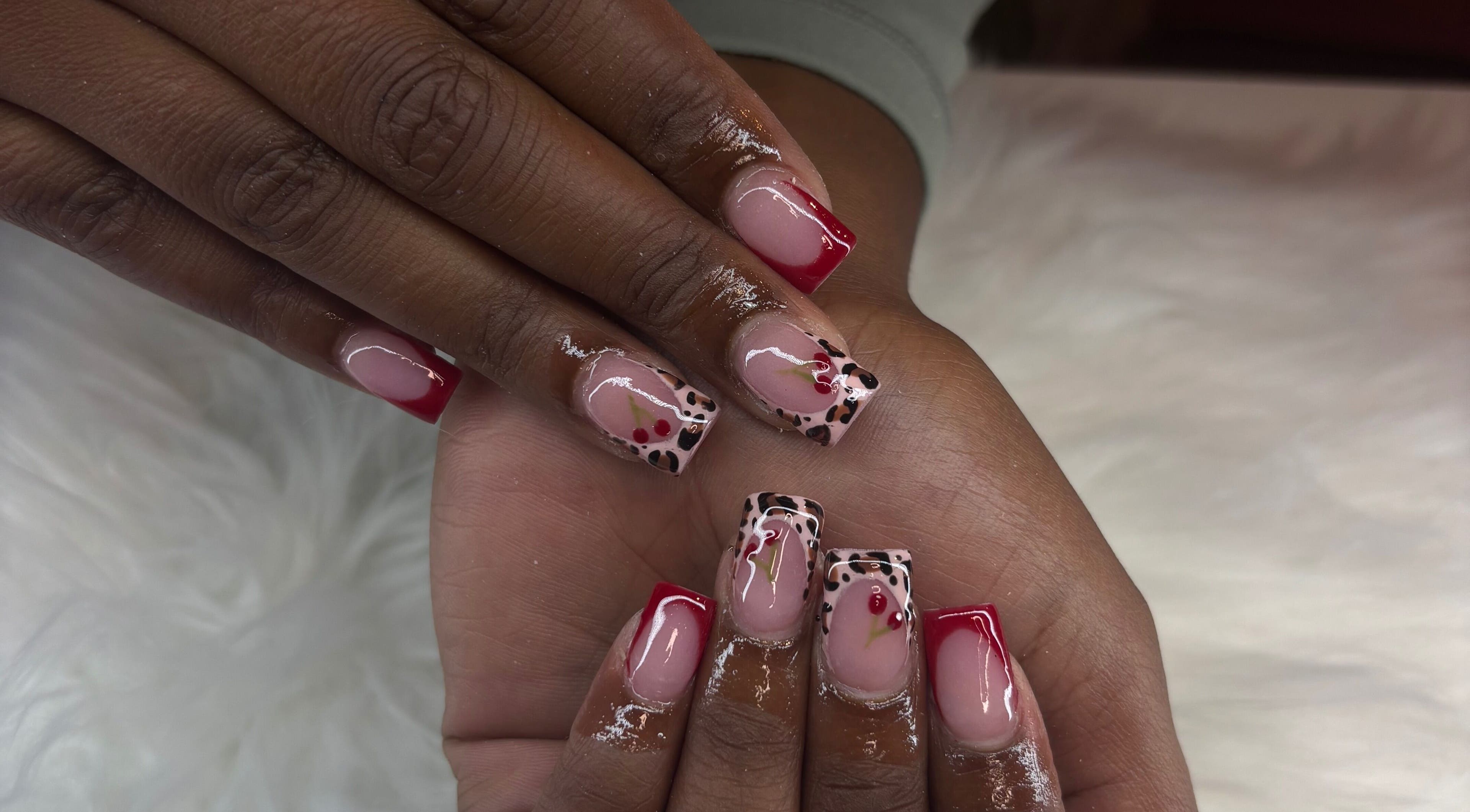 Stylish nail art at Certified Lover Nails in Mitcham, England, GB featuring red tips and floral accents.
