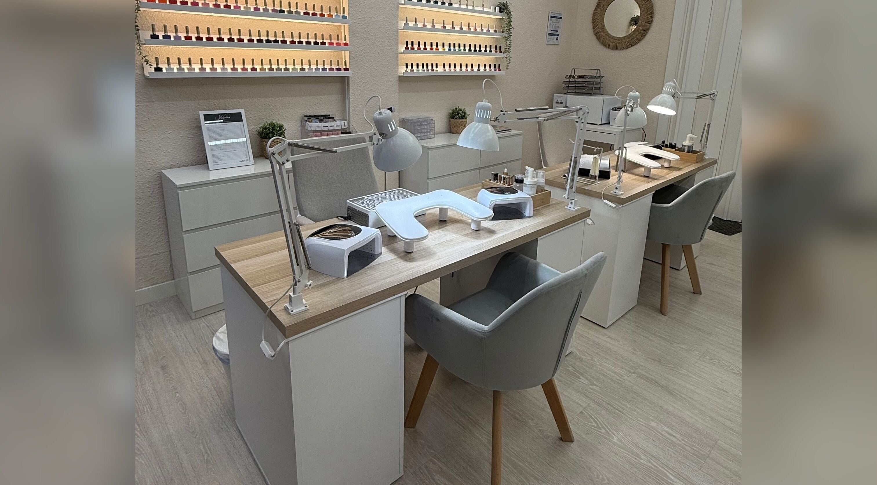 Mesa de manicura moderna en Alejandra Nails, Zaragoza, Aragón, ES, con sillas grises y lámparas.