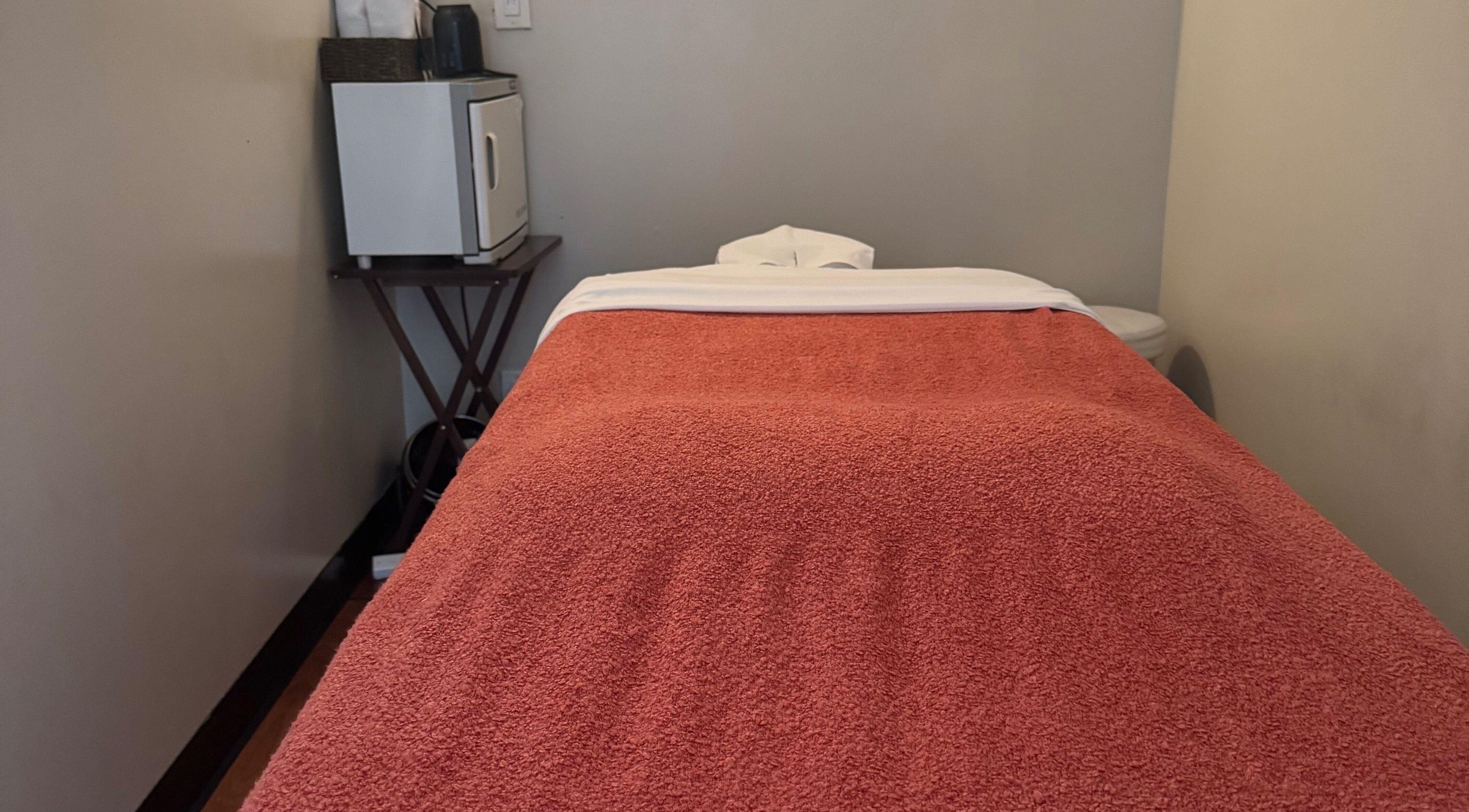 Relax Thai Spa massage room in Redondo Beach, California, featuring a cozy massage bed with warm lighting.
