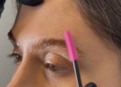 Brow grooming at OF.LAMIMANI, Chicago, Illinois, US. A professional uses a pink brush on eyebrows.
