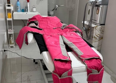 Sala di trattamento presso Sister beauty jv, Candia Lomellina, Lombardia. Tuta di pressoterapia rosa su letto.