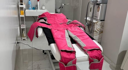 Sala di trattamento presso Sister beauty jv, Candia Lomellina, Lombardia. Tuta di pressoterapia rosa su letto.