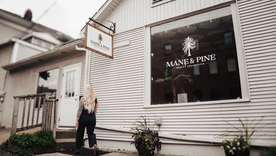 Woman entering Mane & Pine (Laurie Gurr Beauty) in East Aurora, New York, US, showcasing modern salon exterior.