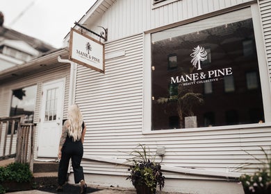 Woman entering Mane & Pine (Laurie Gurr Beauty) in East Aurora, New York, US, showcasing modern salon exterior.
