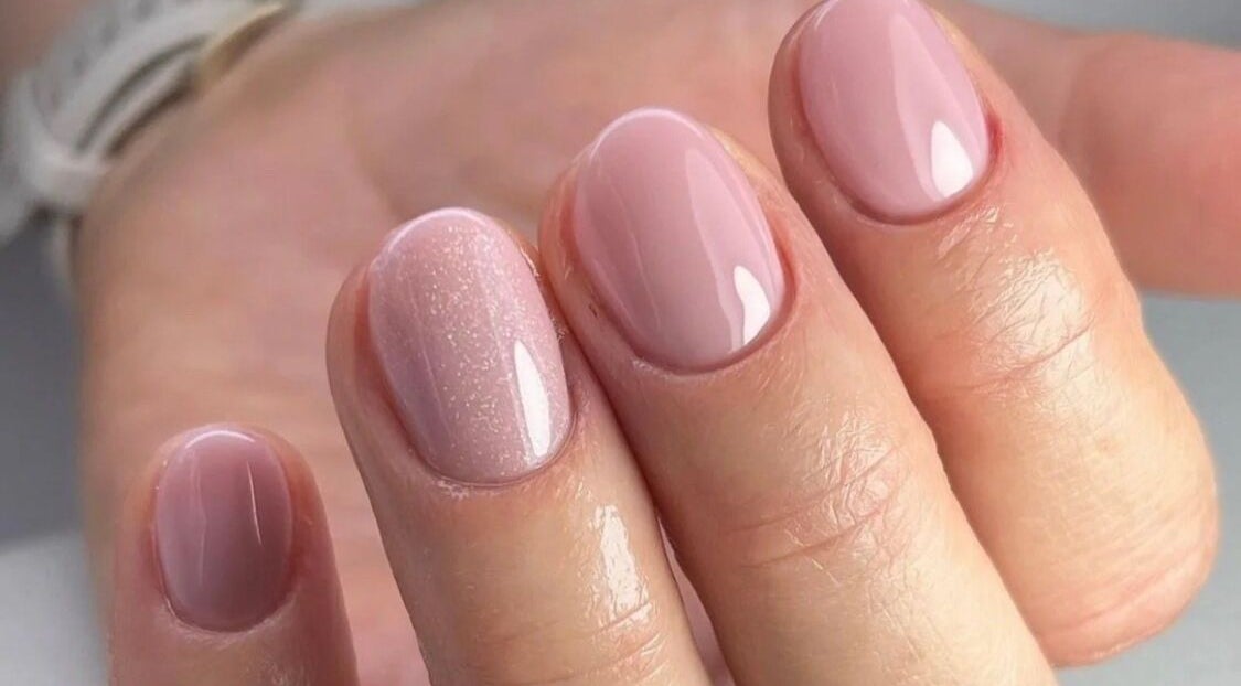Elegant glossy pink manicure at The Beauty Barn, Wilton, England, GB, highlighting nail care expertise.