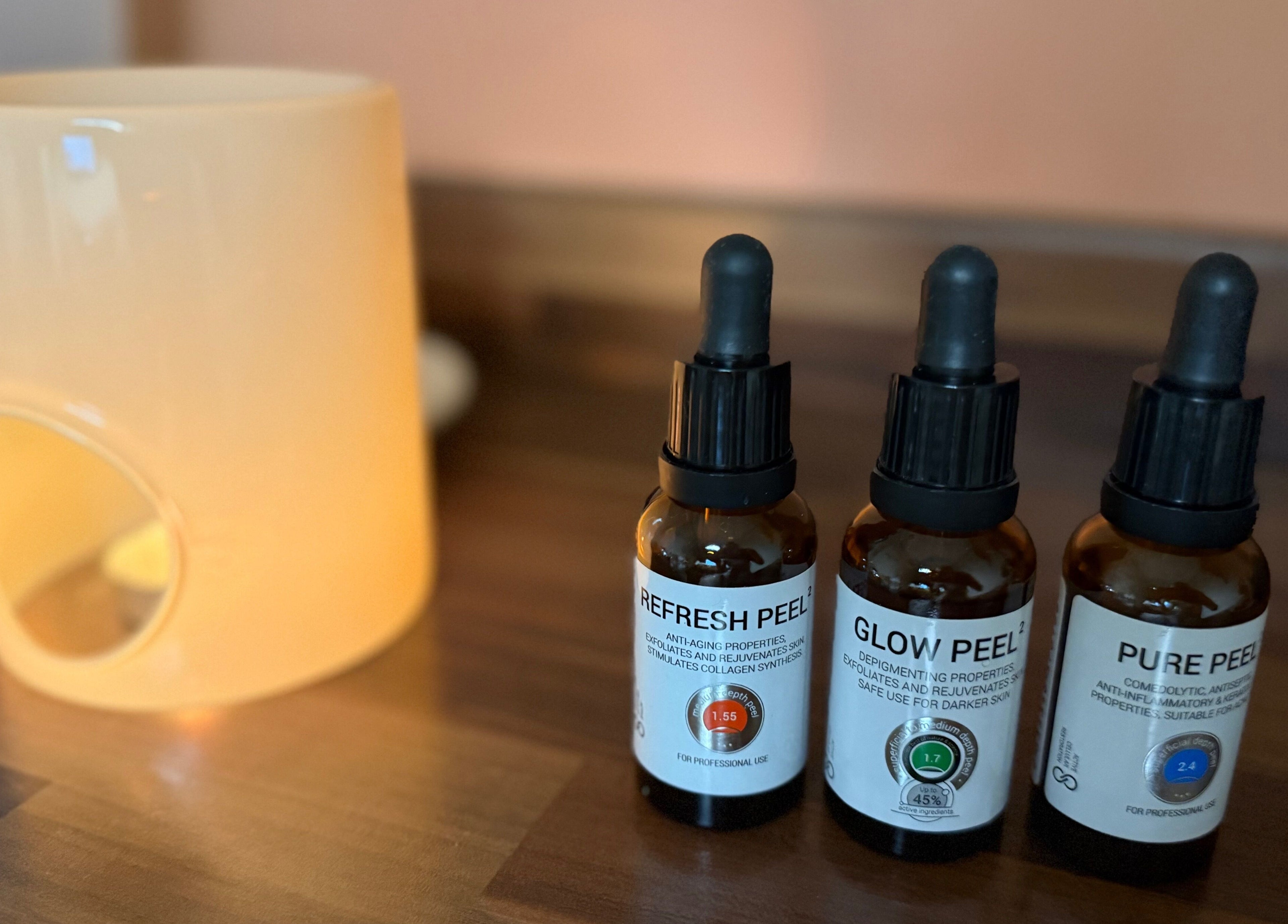 Three skincare serums on a wooden table at KM Skin, Clydebank, Scotland, GB, highlighting rejuvenation products.
