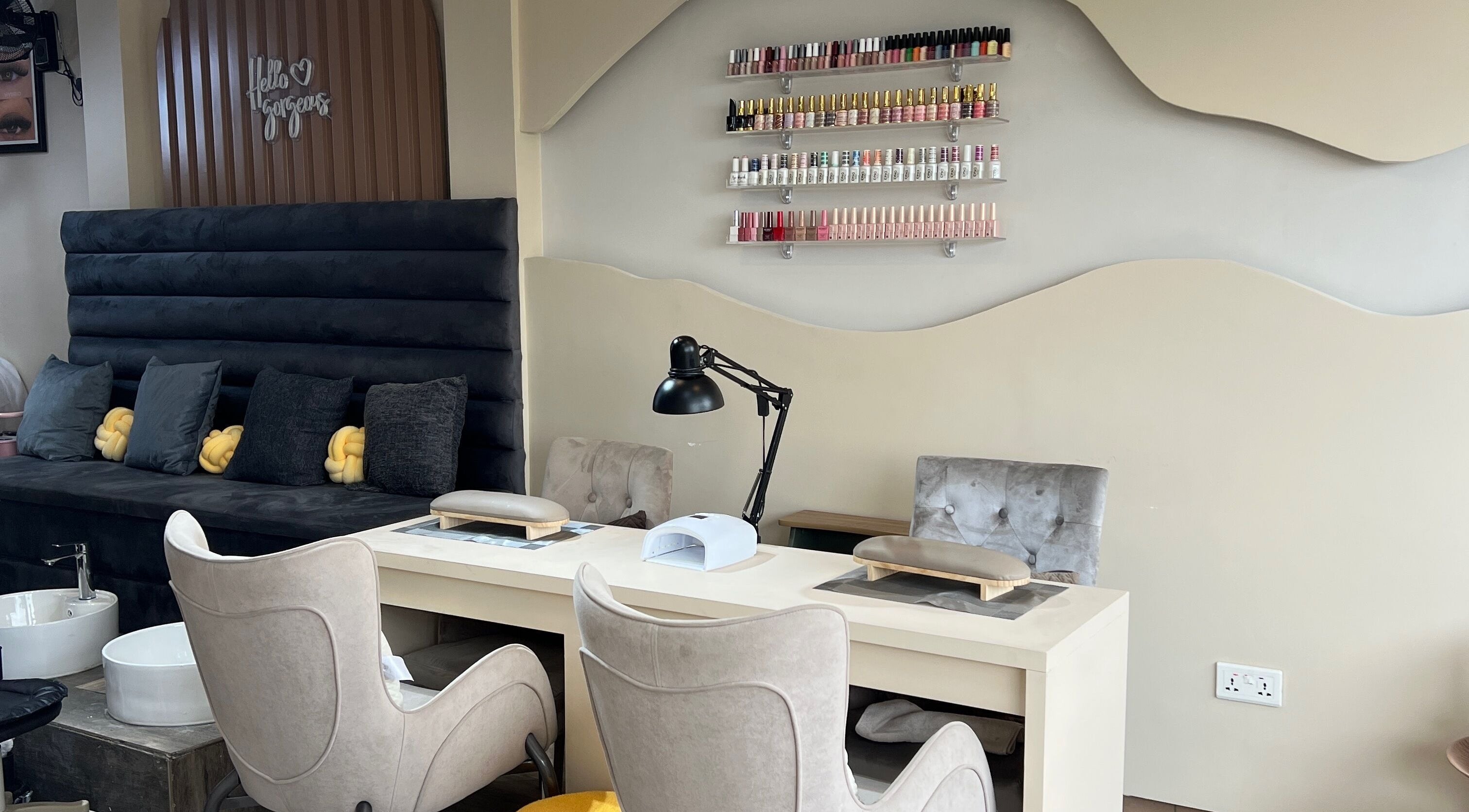 Chic nail salon setup at Niiney Beauty Lounge in Accra, Greater Accra Region, GH, featuring plush seating and nail polish display.