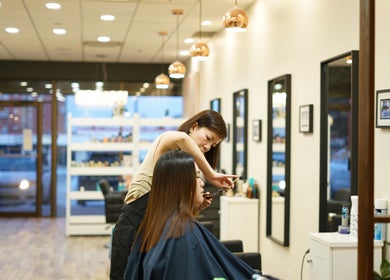 Hair stylist at Thi Vo Hair Salon in Calgary, Alberta, CA working on a client's hair under warm lighting.