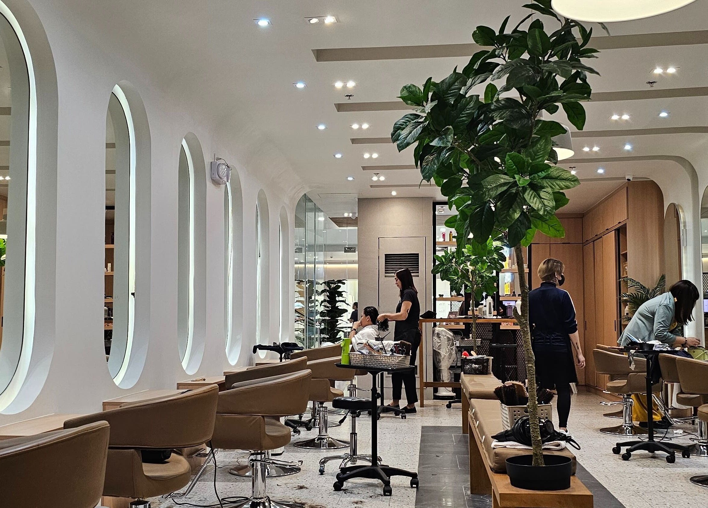 Interior of Azta Urban Salon - One Ayala, Makati, Metro Manila, PH, showcasing modern design with stylist at work.