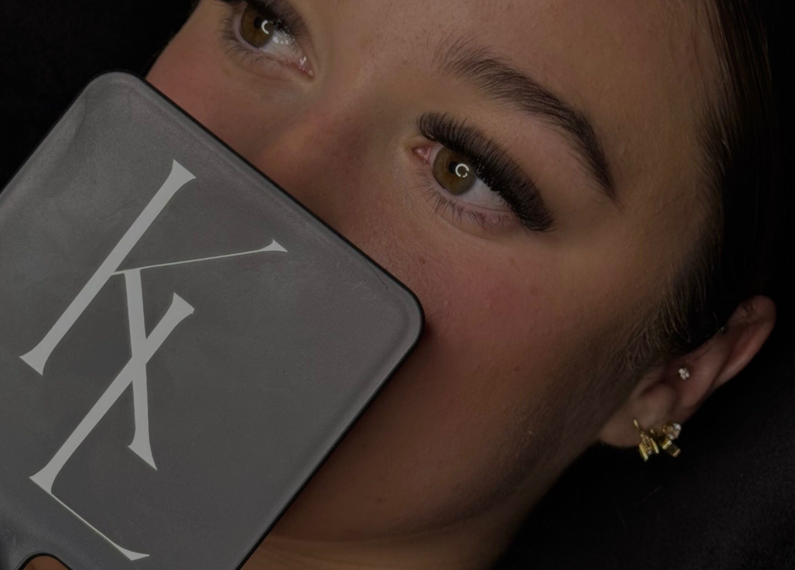 Close-up of woman admiring eyelash extensions in mirror at LASHES BY KL, Tahmoor, New South Wales, AU.