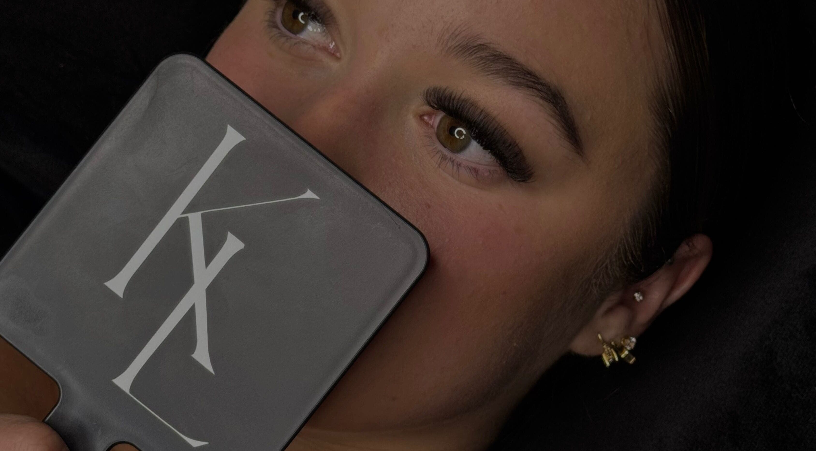 Close-up of woman admiring eyelash extensions in mirror at LASHES BY KL, Tahmoor, New South Wales, AU.